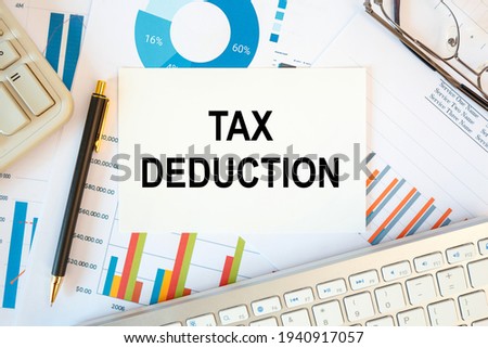 TAX DEDUCTION is written in a document on the office desk with office accessories, keyboard and diagram