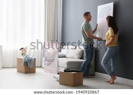 Couple decorating room with pictures together. Interior design Royalty-Free Stock Photo #1940920867
