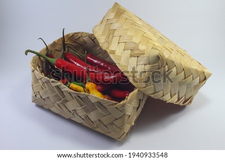 Selective focus of Red chilli peppers in a Besek or traditional woven bamboo basket isolated on white background. 