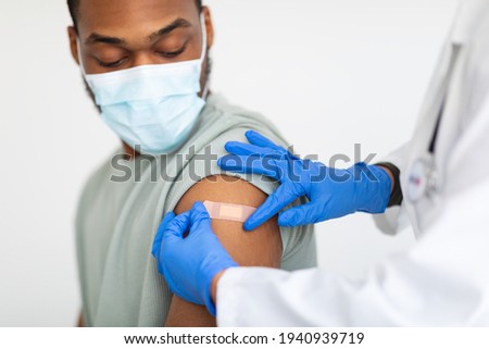 Man Getting Vaccinated Against Covid-19, Doctor Applying Plaster, White Background Royalty-Free Stock Photo #1940939719