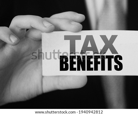 Businessman shows a card with text tax benefits. Taxes and fees policy regulation concept.