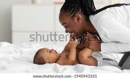 African American mom playing in bed with her black baby
