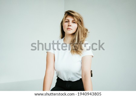 Portrait of handsome blond hair woman posing at the chair in white photo studio