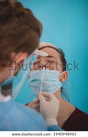 Doctor is testing for coronavirus. A young lady is waiting for a swab from the nose. Collection center. Global pandemic. Unpleasant nose skewers. Royalty-Free Stock Photo #1940948965