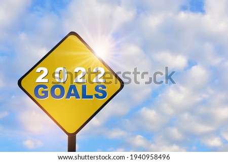 New year 2022 goals on yellow sign on beautiful blue sky with fluffy cloud background. Leadership concept and think different idea