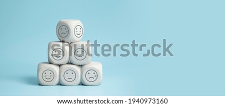 world mental health day concept or feedback rating and positive customer review, wood cube stacking with emotion face icon on blue background Royalty-Free Stock Photo #1940973160
