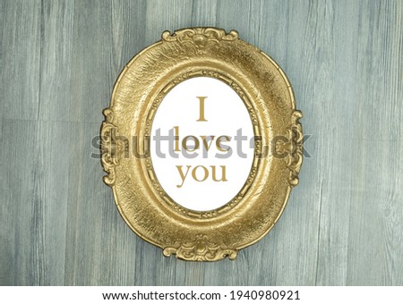 Words inside of oval gold picture frame. Isolated on wooden background