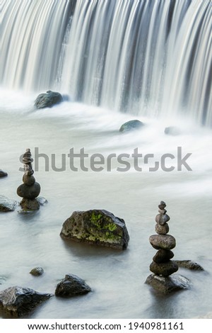 Partially bokeh image piles of stones with stunning curtain waterfall
