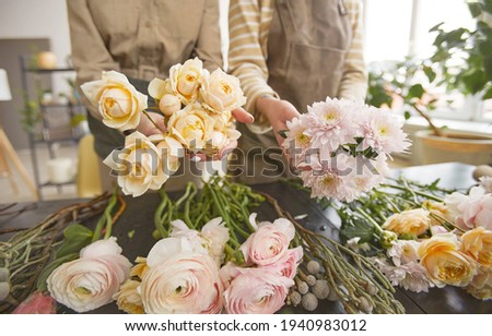 High angle view at beautiful flowers on table in flower shop with two unrecognizable florists arranging bouquets, copy space