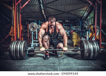 Powerlifter with strong arms lifting weights Royalty-Free Stock Photo #194099144