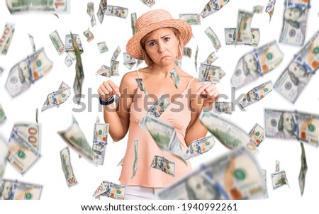 Young blonde woman wearing summer hat pointing down looking sad and upset, indicating direction with fingers, unhappy and depressed.