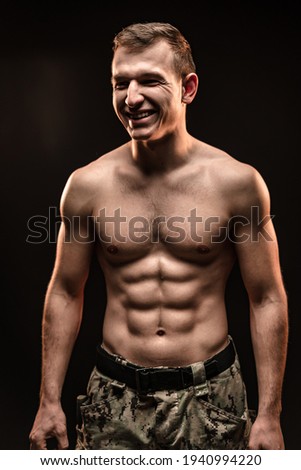 Studio shot of muscular topless military man on black background
