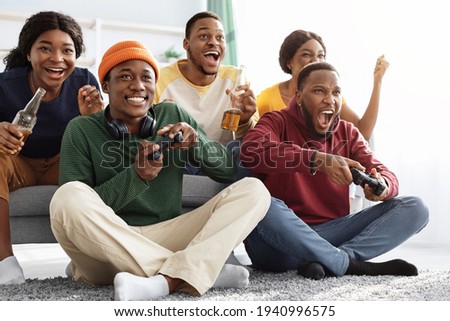 Joyful african american friends playing video games at home Royalty-Free Stock Photo #1940996575