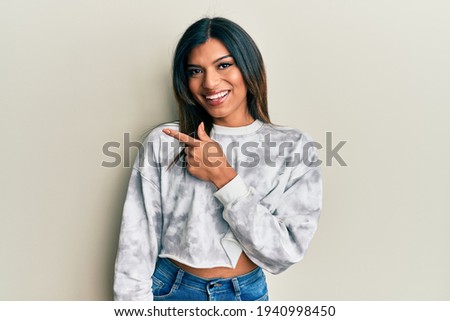 Young latin transsexual transgender woman wearing casual clothes smiling cheerful pointing with hand and finger up to the side 