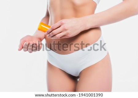 Cropped view of woman in underwear holding jar with pills isolated on white