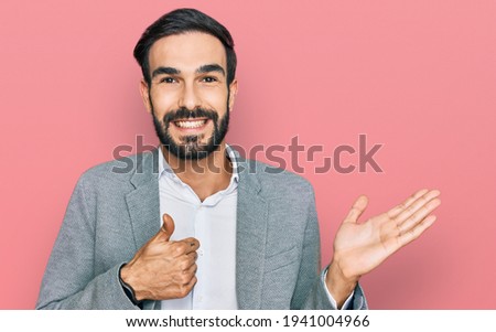 Young hispanic man wearing business clothes showing palm hand and doing ok gesture with thumbs up, smiling happy and cheerful 