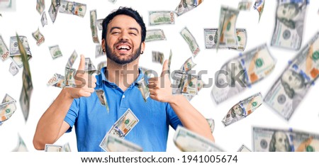 Young hispanic man wearing casual clothes success sign doing positive gesture with hand, thumbs up smiling and happy. cheerful expression and winner gesture.