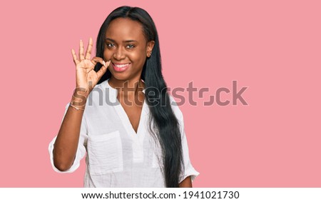Young black woman wearing casual clothes smiling positive doing ok sign with hand and fingers. successful expression. 