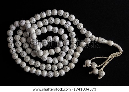 White rosary (tespih) isolated on black background. Horizontal close-up. Patience, prayer, religious icons and symbols concepts.