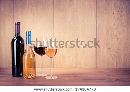 Wine glasses and bottles front wooden background