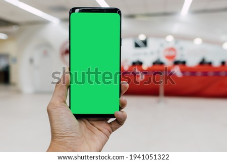 Hand of people holding smartphone with green screen mockup using mobile check-in at the airport
