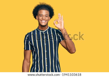 African american man with afro hair wearing casual clothes smiling positive doing ok sign with hand and fingers. successful expression. 