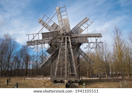 old wooden mill against the sky and spring forest