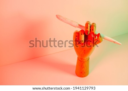 Wooden hand with a white paintbrush with red lights