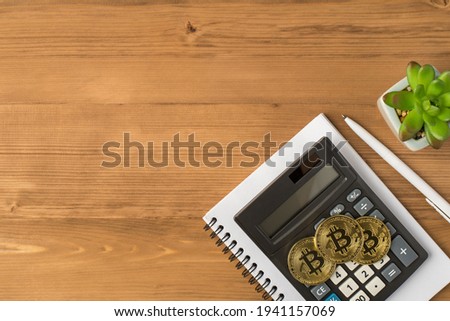 Top view photo of workplace with pen plant three gold coins with bitcoin symbol and calculator on notebook on isolated wooden table background with copyspace
