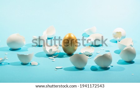 Intact golden egg among broken white eggs. The concept of reliability, resistance to adverse conditions. Royalty-Free Stock Photo #1941172543