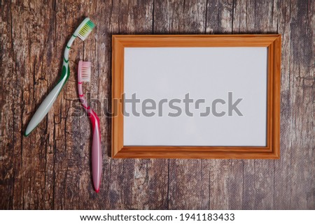 Toothbrushes and empty boho style photo frame on wooden background. Isolated white light wood frame layout horizontal signage for artwork, lettering or logo. Copyright space for site