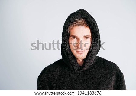 Portrait of a young man in black sweatshirt with hood on a white background. Copy, empty space for text.
