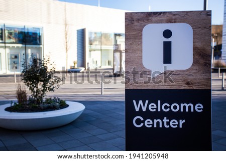 An information sign stands in the middle of the city. The sign says "Welcome Center".