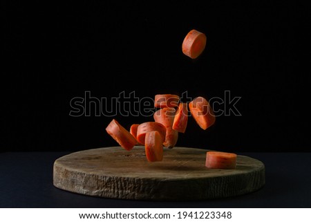 Carrots on a dark background. Sliced carrots fall on a wooden board on a black background. Healthy food