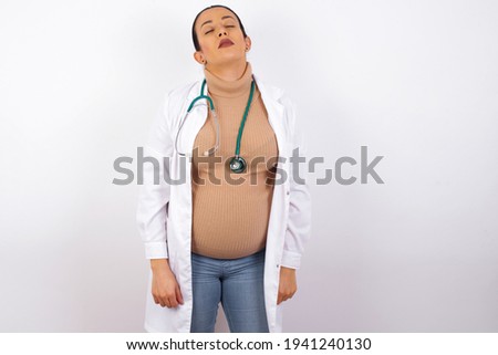 young pregnant doctor woman wearing medical uniform against white background looking sleepy and tired, exhausted for fatigue and hangover, lazy eyes in the morning.