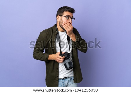 Photographer man over isolated purple background covering mouth and looking to the side
