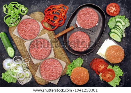 Cheeseburger Ingredients  And Cast Iron Grill Pan, Overhead View. Ground Beef Meat Cutlets or Patties and Vegetables on Wooden Chopping Board. Homemade Cooking Food For Family Party, Top View.