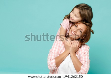 Happy woman in pink clothes have fun with child baby girl 5-6 years old Mommy little kid daughter stand behind hug kiss isolated on pastel blue azure background studio Mother's Day love family concept