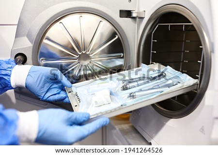 Nurse putting instruments in special craft paper bags into autoclave for processing.Laboratory equipment. Tools sterilization, bacterial purification and disinfection in dental clinic. Selective focus Royalty-Free Stock Photo #1941264526