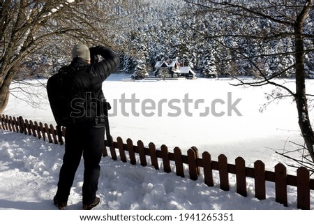 photographer man in the guest house by the frozen lake, in the snow-covered forest