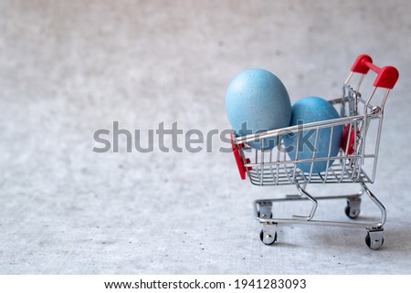 Easter eggs in a shopping cart on gray concrete background
