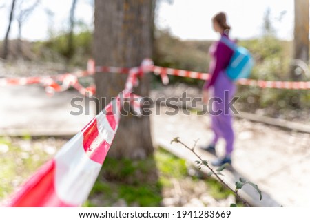 A female hiker behind a barricade tape at a restricted hiking area Royalty-Free Stock Photo #1941283669