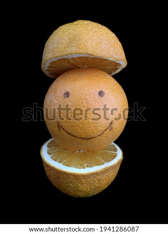 Ripe orange with a smile pattern. Yellow fruits, whole and in a cut, isolated on black. Citrus with a picture of a cheerful face. Concept: joy, positive, smile, happiness