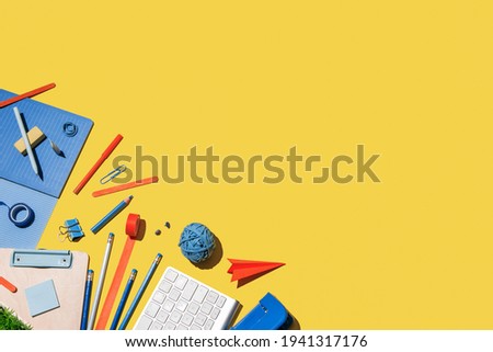 Creative mess of colourful supplies on yellow background.