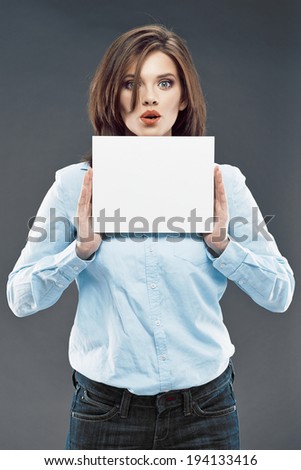 Young surprised business woman studio portrait with white board on gray background.