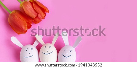 Bright Easter composition - pink eggshells of hares and red tulips on a pink background. Background for greeting cards, invitations, greetings.