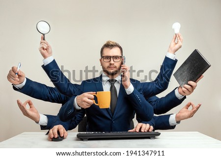Businessman with many hands in a suit. Works simultaneously with several objects, a mug, a magnifying glass, papers, a contract, a telephone. Multitasking, efficient business worker concept Royalty-Free Stock Photo #1941347911