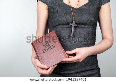 Law and Ethics. Woman with a wooden cross around her neck and a book in hands.