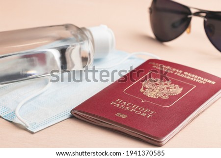 Safe travel during coronavirus pandemic concept. Protective medical mask, sunglasses, sanitizer and Russian passport on the table