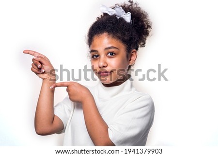 An Afro American teenage girl pointed the fingers aside, confident, isolated on a white background